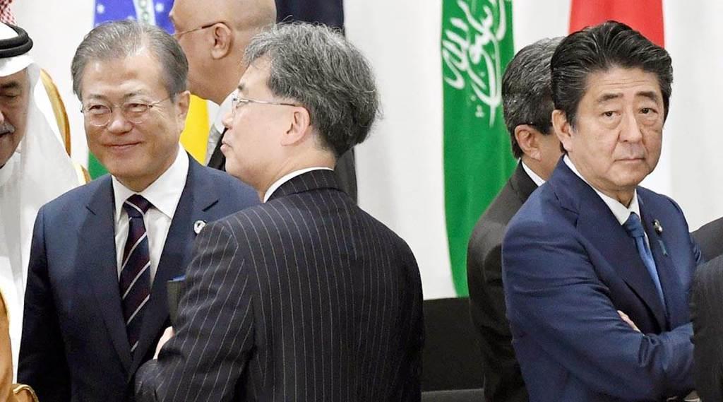 G20大阪サミットで、韓国の文在寅大統領(手前左から2人目)と握手を交わした後、厳しい表情を見せる安倍晋三首相(中央右)=6月29日、大阪市住之江区(代表撮影)