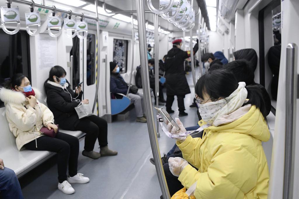 中国・北京でマスクやビニールの手袋をして地下鉄に乗る市民。朝の通勤時間帯だが利用客は少ない =2月24日(共同)
