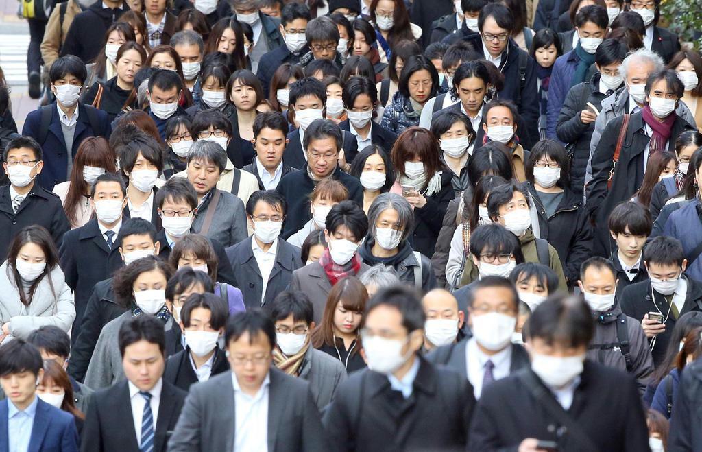 新型コロナウイルスの感染が拡大する中、マスクを着けて通勤する人たち=東京都中央区