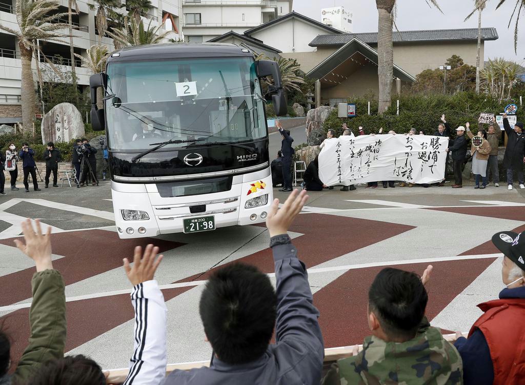 市民らに見送られて「勝浦ホテル三日月」を出発する中国・武漢からの帰国者を乗せたバス＝２月１３日、千葉県勝浦市