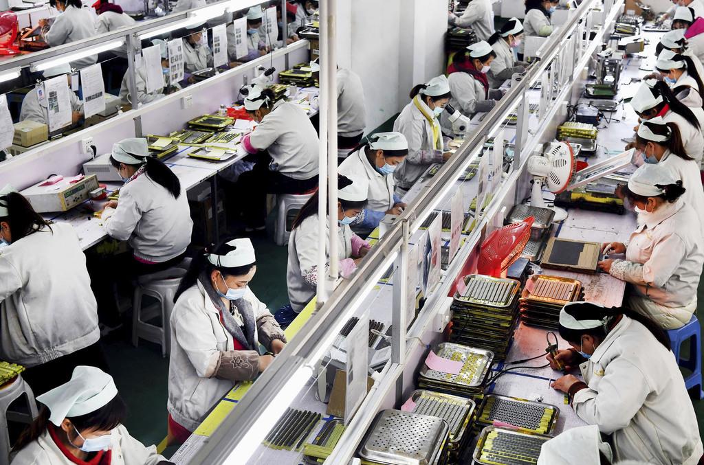 生産活動を再開した企業の工場で、マスクを着用して働く労働者=4日、中国陝西省(新華社=共同)