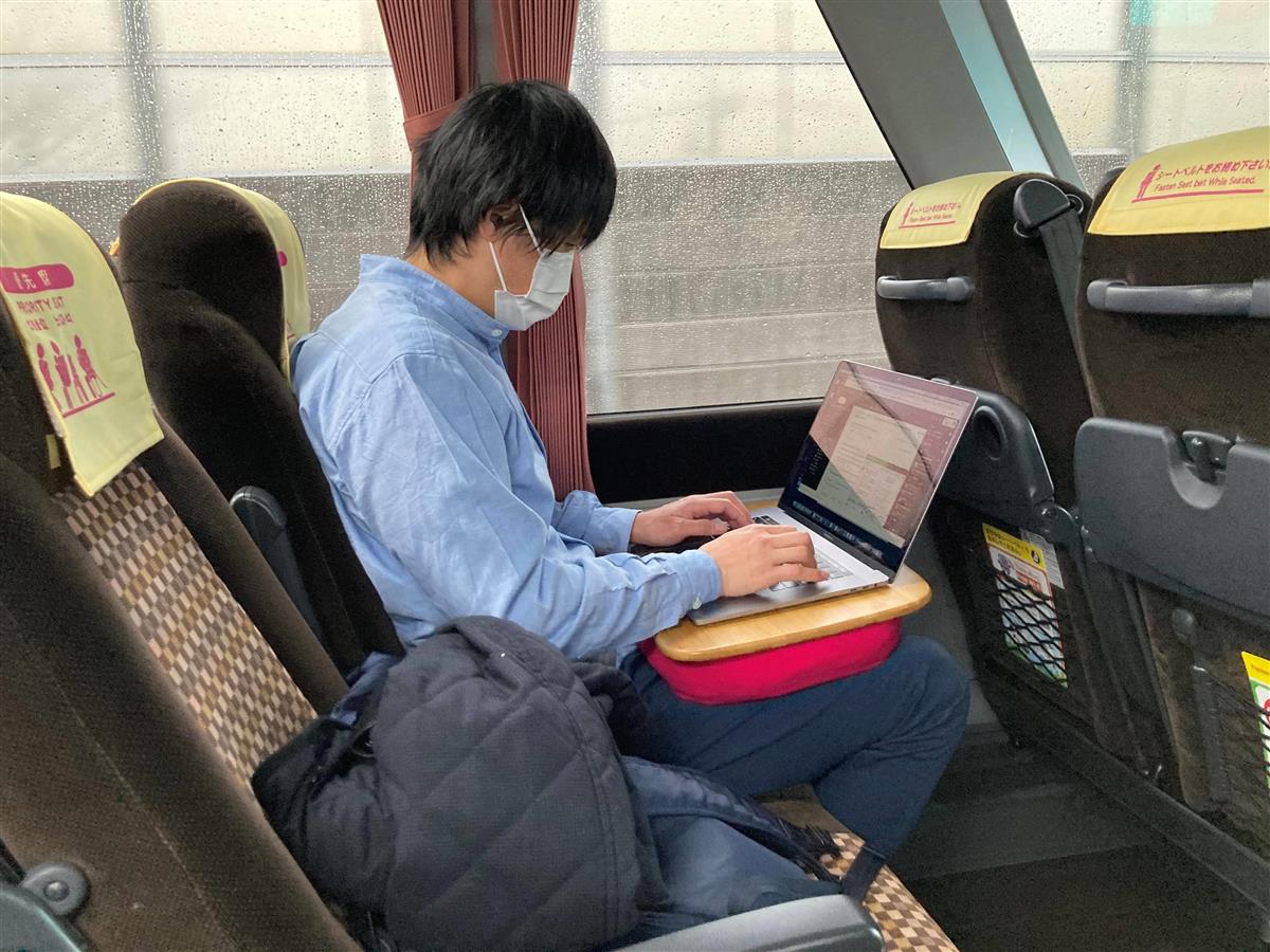 インターネットが通じるバス車内で仕事をする乗客。パソコン作業がしやすいようにクッションも貸し出される（東急提供）