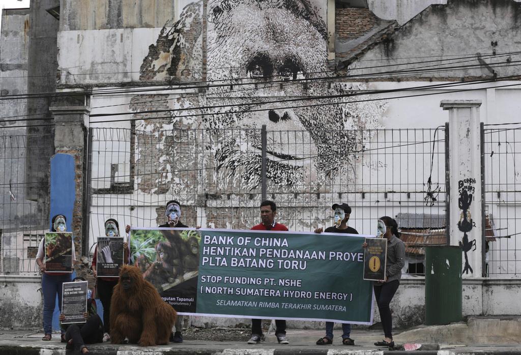 オランウータンの壁画の前でダム建設に抗議する人々=1日、インドネシア北スマトラ州(AP)