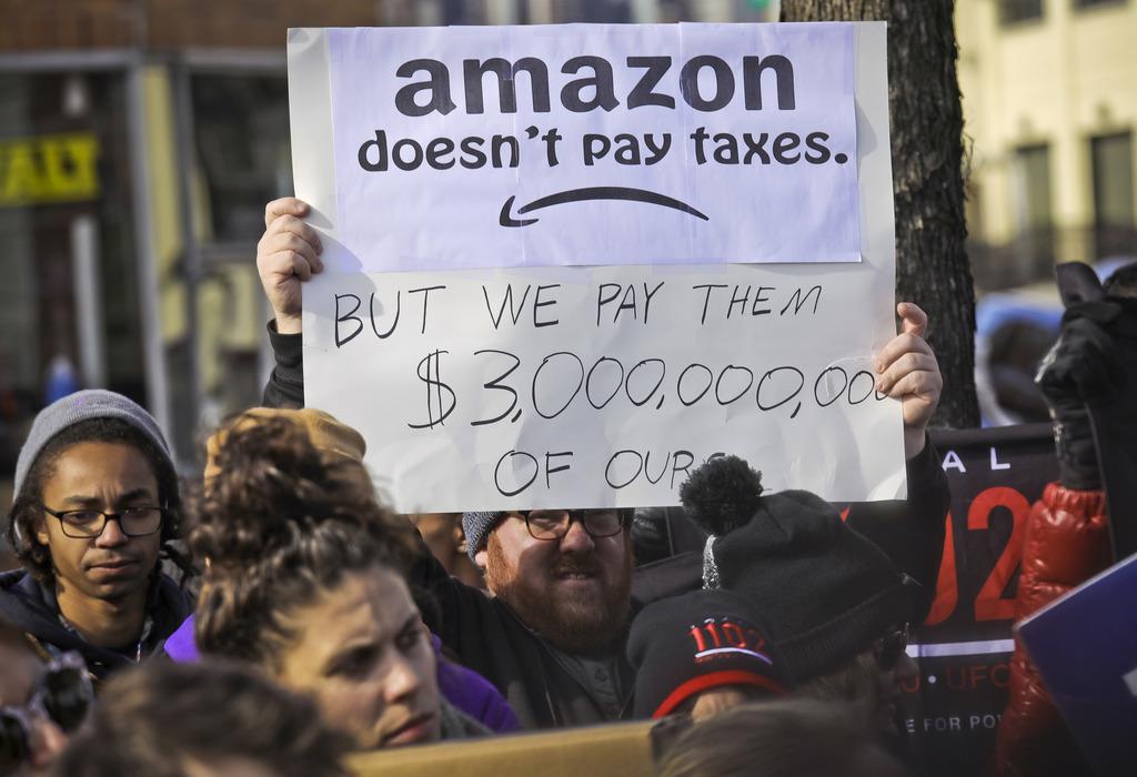 2018年11月、米ニューヨークで、アマゾンを批判するプラカードを掲げ、同社の「第2本社」計画に反対するデモ隊(AP)
