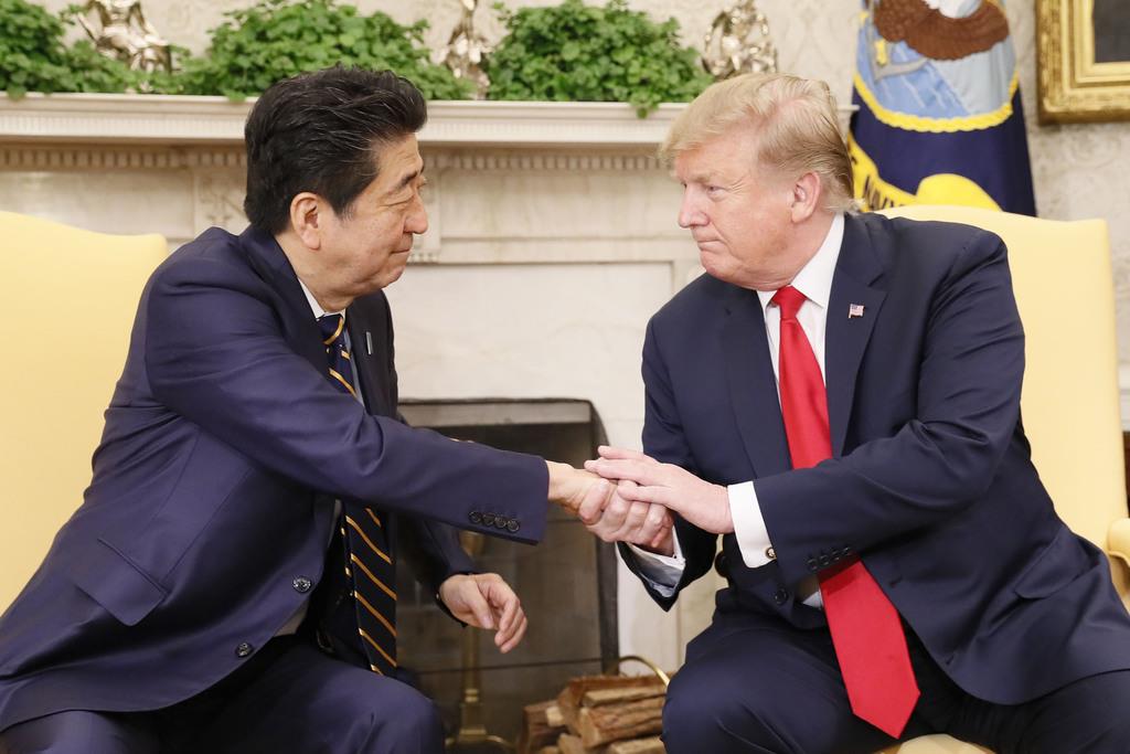 握手する安倍首相(左)とトランプ米大統領=26日、ワシントンのホワイトハウス(共同)