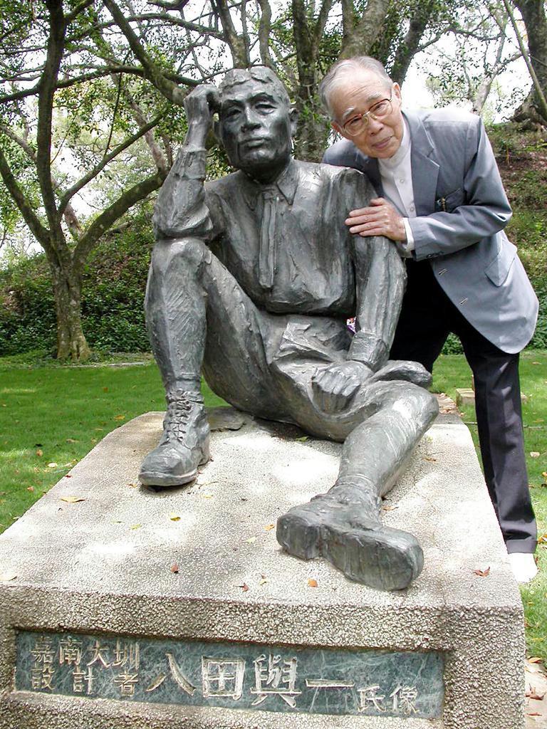 台湾・台南の烏山頭ダムで2003年に行われた八田與一の慰霊祭に参列し、像に寄り添う元測量技師の顔雲霄=同年5月8日(河崎真澄撮影)