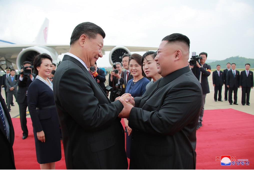 20日、平壌国際空港で中国の習近平国家主席(左)と握手する金正恩朝鮮労働党委員長(朝鮮中央通信=朝鮮通信)