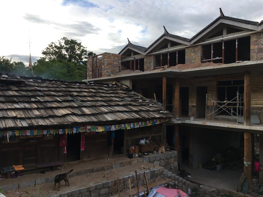 築400年以上という古い民家の隣で建築中の旅館=雲南省ジャシ村(藤本欣也撮影)