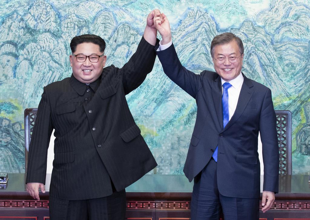北朝鮮の金正恩朝鮮労働党委員長(左)と手を掲げる、韓国の文在寅大統領=2018年4月27日(AP)