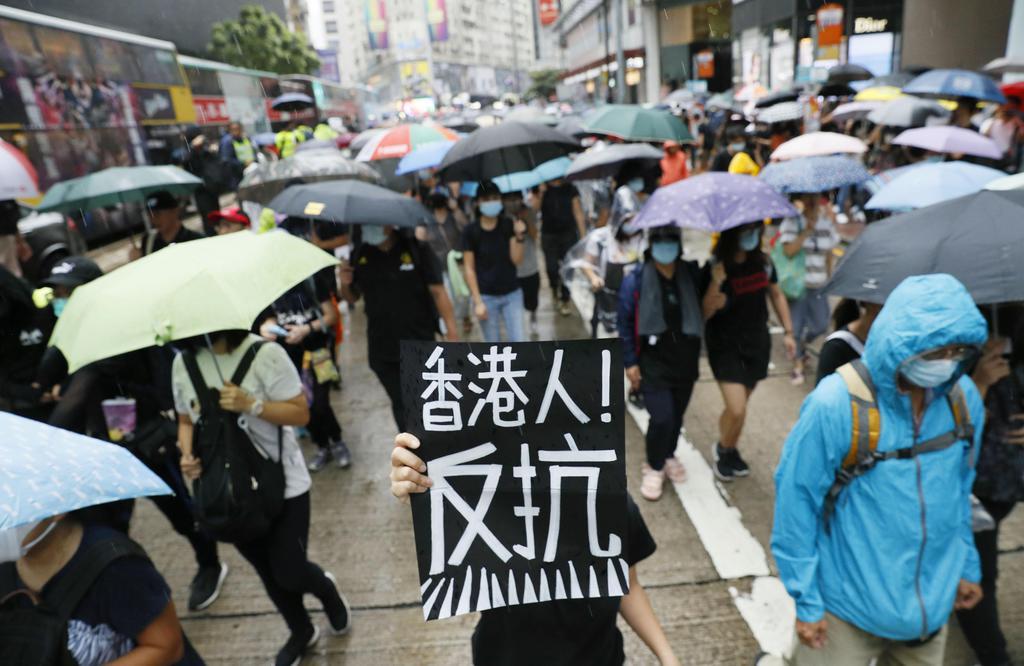 「覆面禁止法」の施行や警察の発砲に抗議し、デモ行進する人たち=6日、香港(共同)