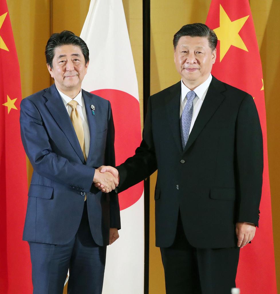 中国の習近平国家主席(右)と握手する安倍首相=6月27日、大阪市内のホテル