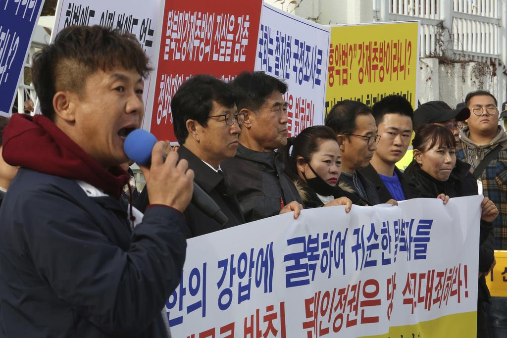 亡命を希望した北朝鮮の船員2人を強制送還した文在寅政権の決定に抗議する脱北者団体のデモ=12日、ソウル(AP)