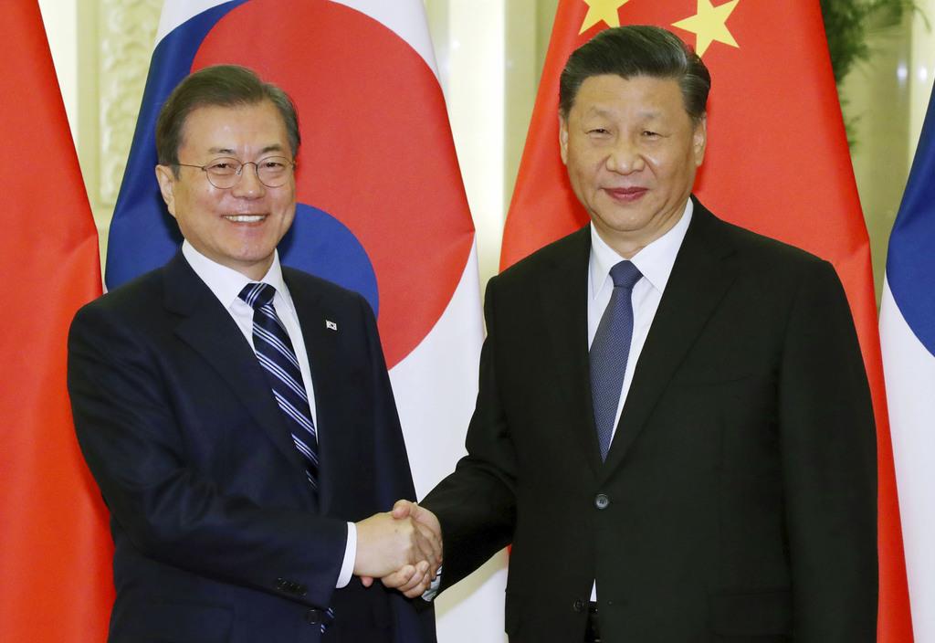 握手する中国の習近平国家主席（右）と韓国の文在寅大統領＝２３日、北京（聯合＝共同）