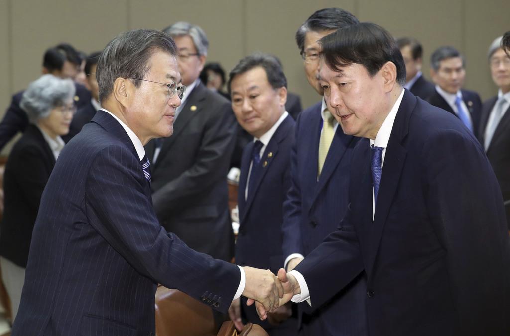 ソウルの大統領府で開かれた会議で握手する文在寅大統領(手前左)と尹錫悦検事総長=2019年11月8日(聯合=共同)