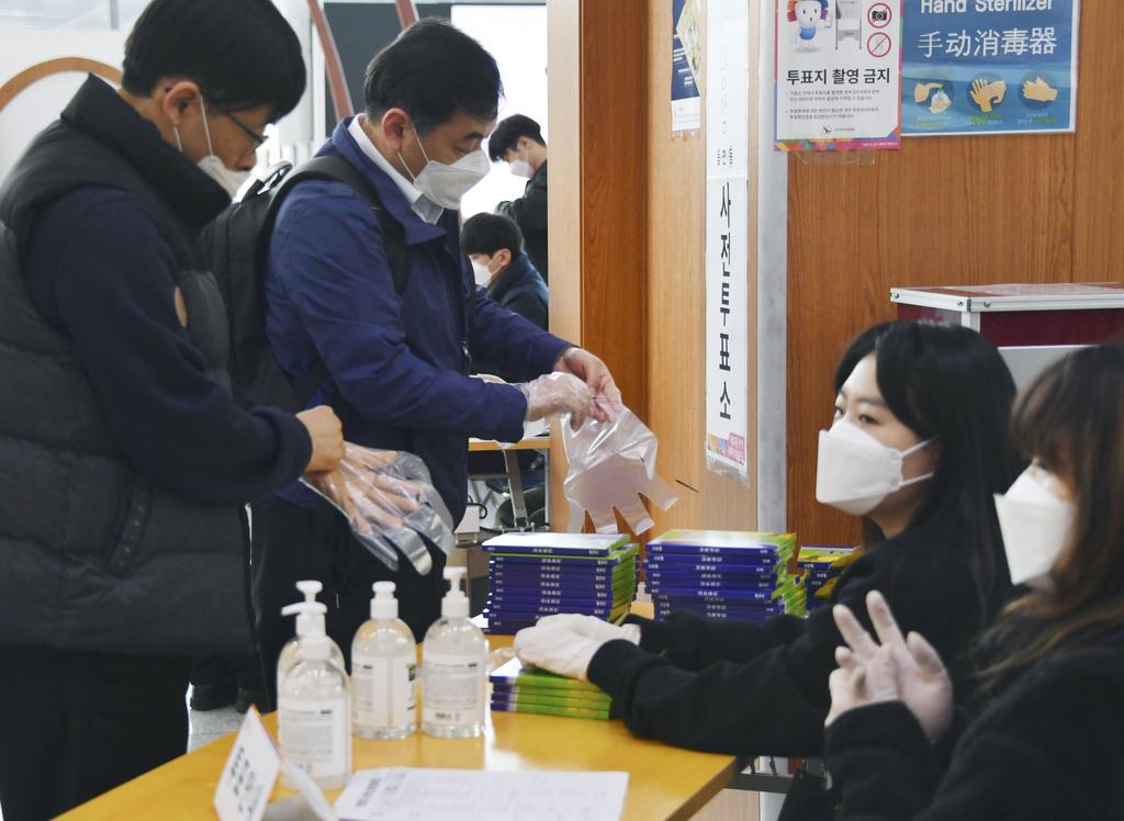 韓国総選挙の事前投票で、新型コロナウイルス対策のビニール製手袋を着ける有権者＝１０日、ソウル駅（共同）