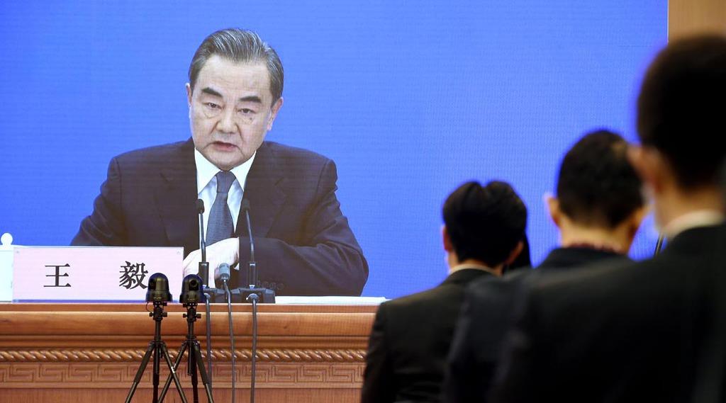 記者会見する中国の王毅国務委員兼外相を映すモニター。新型コロナウイルスの感染対策で報道陣は別会場から取材した=24日、北京(共同)