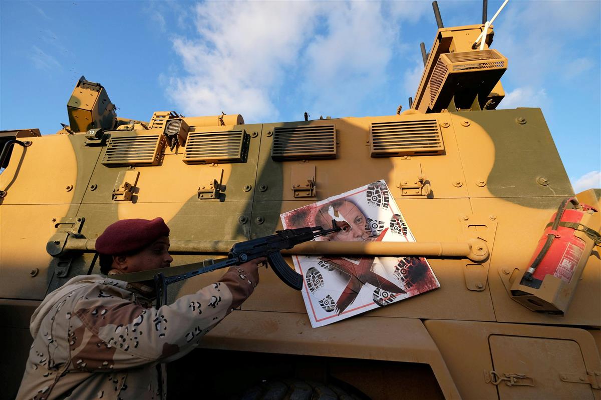 リビアのベンガジで、トルコのエルドアン大統領の写真に銃口を向ける「リビア国民軍」(LNA)の戦闘員=今年1月(ロイター)