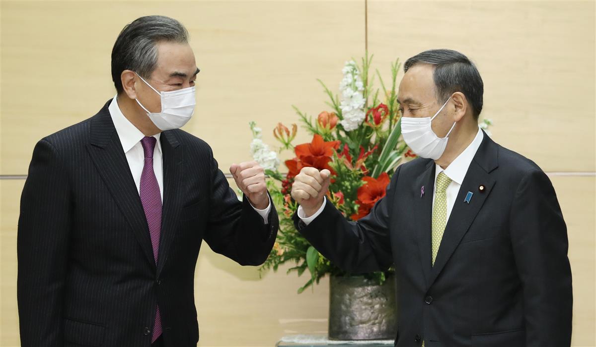 会談を前に中国の王毅国務委員兼外相(左)とグータッチを交わす菅義偉首相=11月25日、首相官邸(春名中撮影)