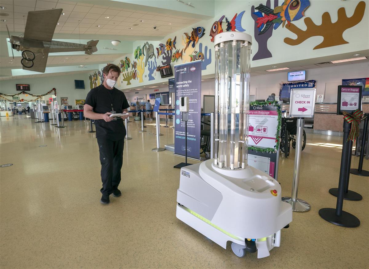 米フロリダ州の空港で、紫外線を放つロボットを動かす感染対策の専門家=2020年12月9日(AP=共同)