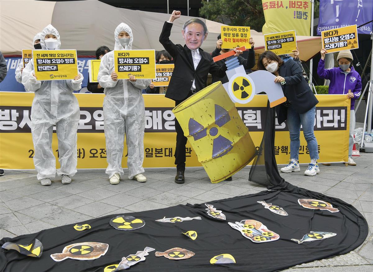 13日、ソウルの在韓国日本大使館周辺で、福島第1原発処理水の海洋放出に反対する環境団体。菅義偉首相の面を付けた人物が真っ黒な水を垂れ流すパフォーマンスをしている(共同)