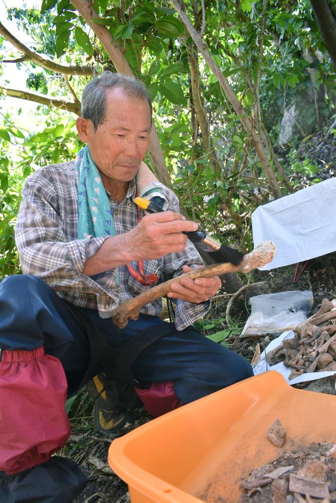 収容した遺骨の泥をはらう山崎功さん=6月17日、テニアン島(池田祥子撮影)