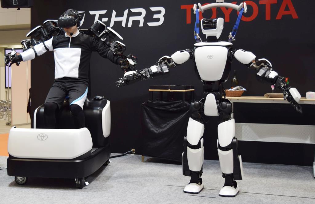 操縦者(左)に合わせて動く人型ロボット「T-HR3」=東京都江東区