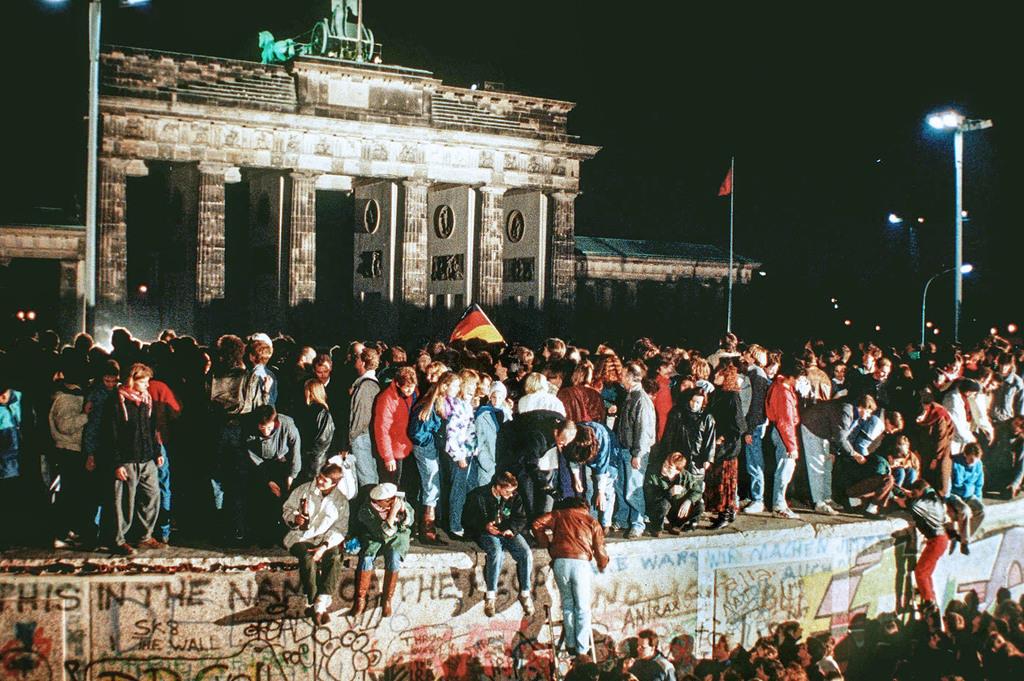 1989年11月9日、東西ドイツの国境開放後にベルリン・ブランデンブルク門前の「ベルリンの壁」の上に立つ人々。壁の崩壊は共産主義の終わりを印象づけた(DPA提供・AP=共同)