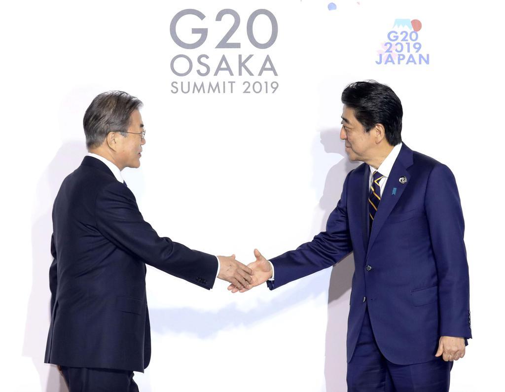 G20大阪サミットで韓国の文在寅大統領(左)を迎える安倍首相=28日午前、大阪市(代表撮影)