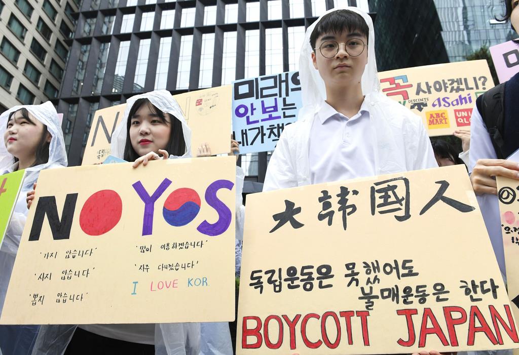 26日、ソウルの日本大使館前で日本製品の不買を呼び掛ける韓国市民ら(共同)