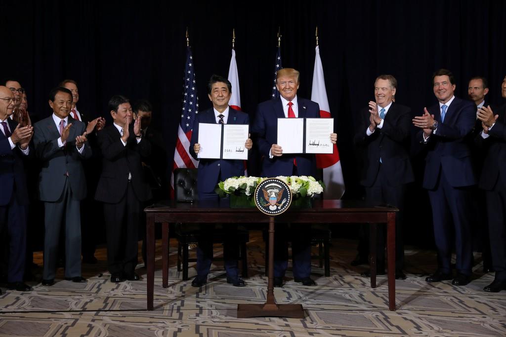 トランプ米大統領(右から4人目)と一緒に協定書を披露する安倍晋三首相(同5人目)=25日、ニューヨーク(ロイター)