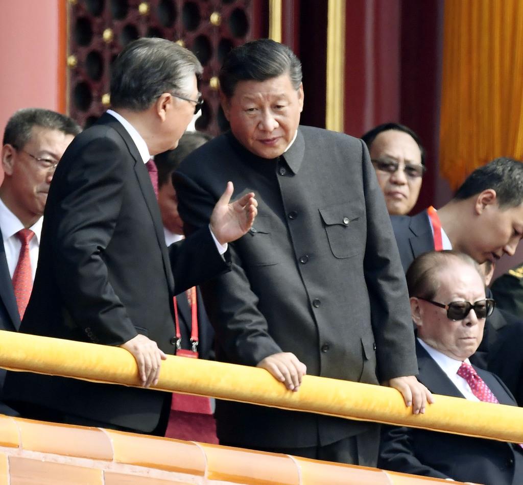 中国建国７０年の記念式典で、胡錦濤前国家主席（左）と話す習近平国家主席＝１０月１日、北京の天安門（共同）