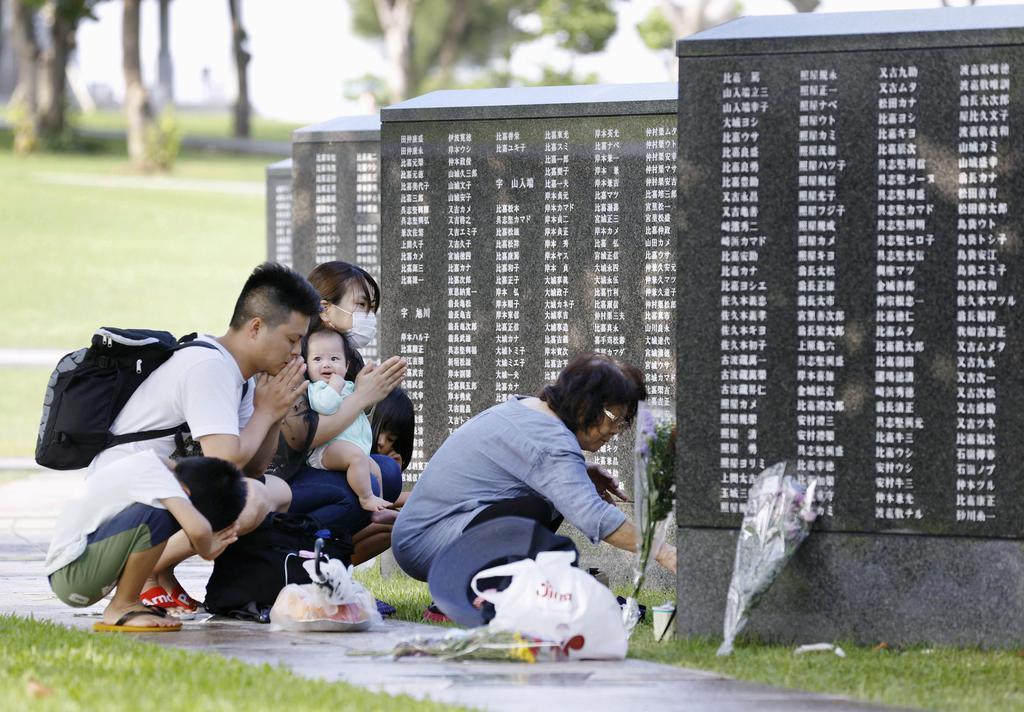 沖縄戦で犠牲となった親族の氏名が刻まれた「平和の礎」に手を合わせ、悼む遺族＝２３日午後、沖縄県糸満市の平和祈念公園