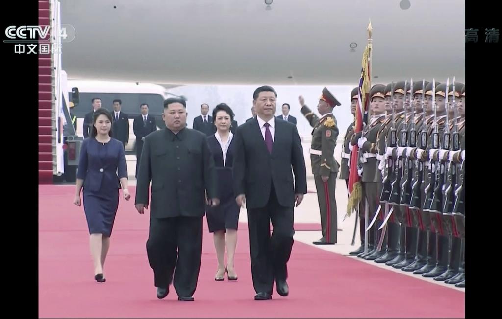 ２０日、平壌国際空港に到着し、北朝鮮の金正恩朝鮮労働党委員長（前方左）とともに儀仗兵の前を歩く中国の習近平国家主席（前方右）。中国中央テレビの映像から（ＡＰ）