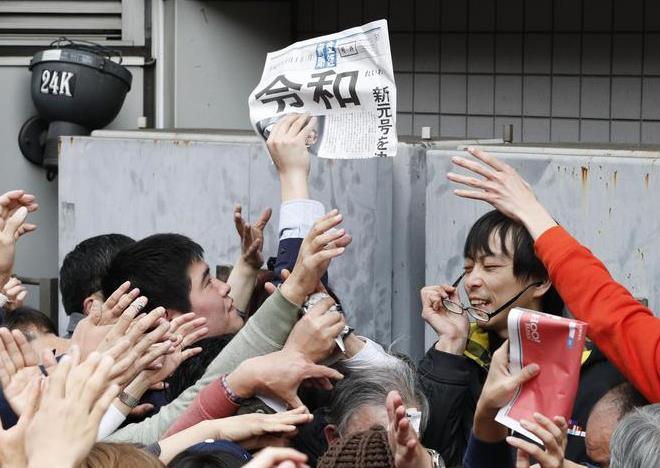 新元号「令和」が発表され、新橋駅前で配布される号外に手を伸ばす大勢の人たち=1日午後、東京都港区