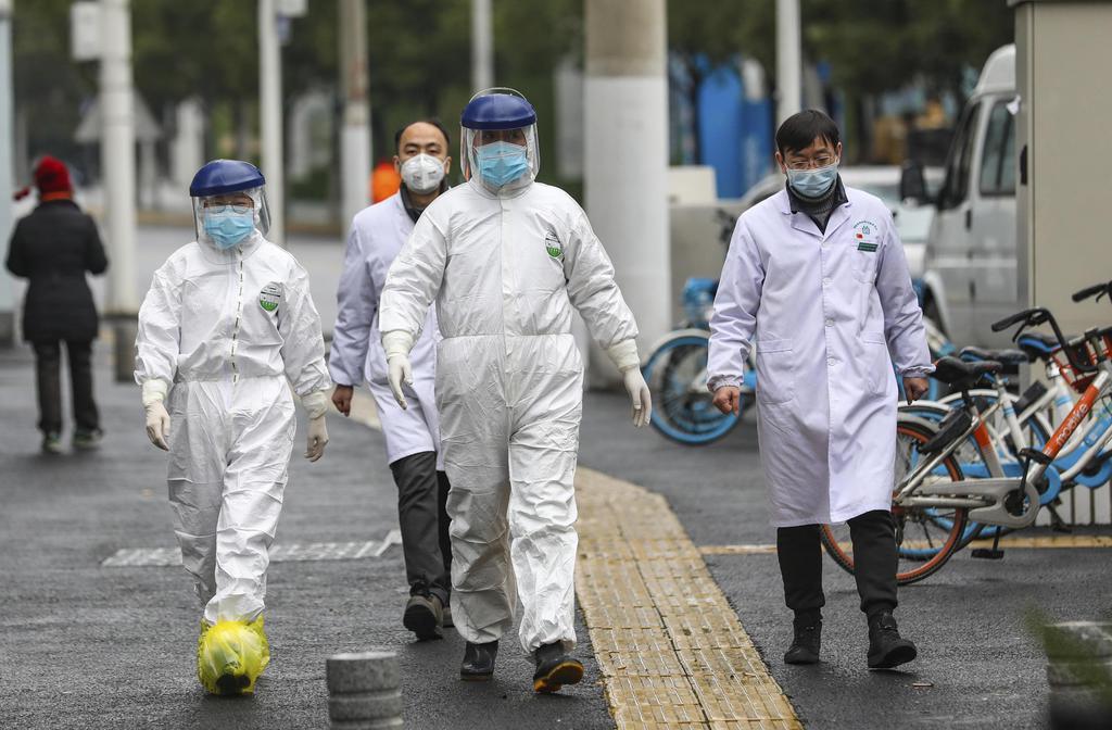 防護服を着て中国・武漢市内を歩く医療従事者=26日(AP=共同)