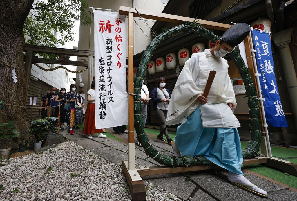 大阪市中央区の少彦名神社で行われた「夏越の祓」で、茅の輪をくぐる神職=29日午後