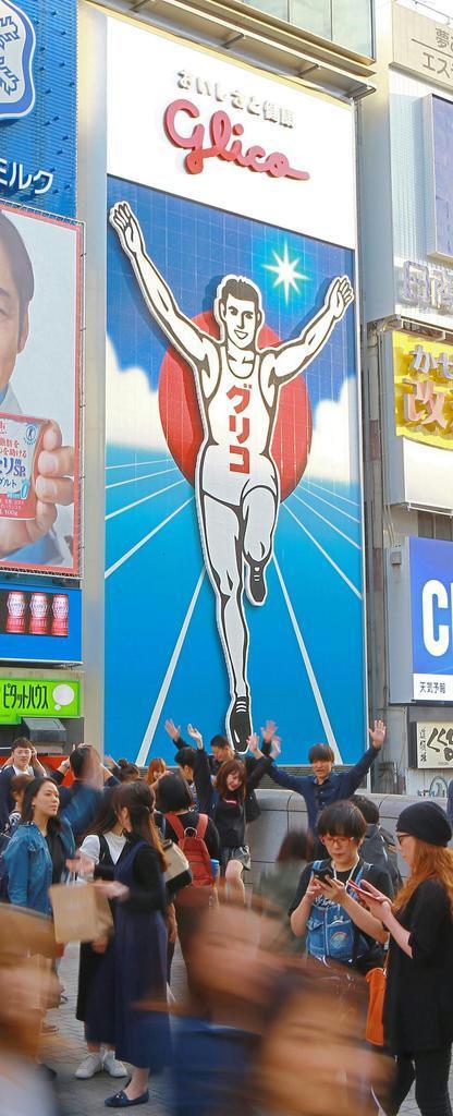グリコの看板を背に両手を挙げ、ポーズを取る観光客ら。大阪の人気ナンバーワンスポットは終日大にぎわいだ(渡辺恭晃撮影)
