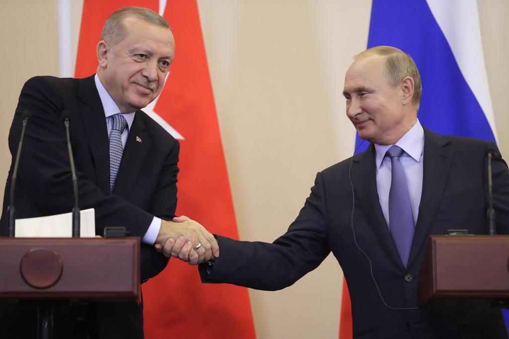 10月22日、ロシア南部ソチで握手するロシアのプーチン大統領(右)とトルコのエルドアン大統領(タス=共同)