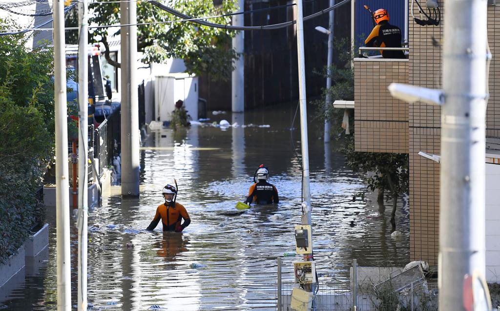 台風19号の影響で、川が氾濫して冠水した川崎市内を歩く消防隊員=10月13日午前