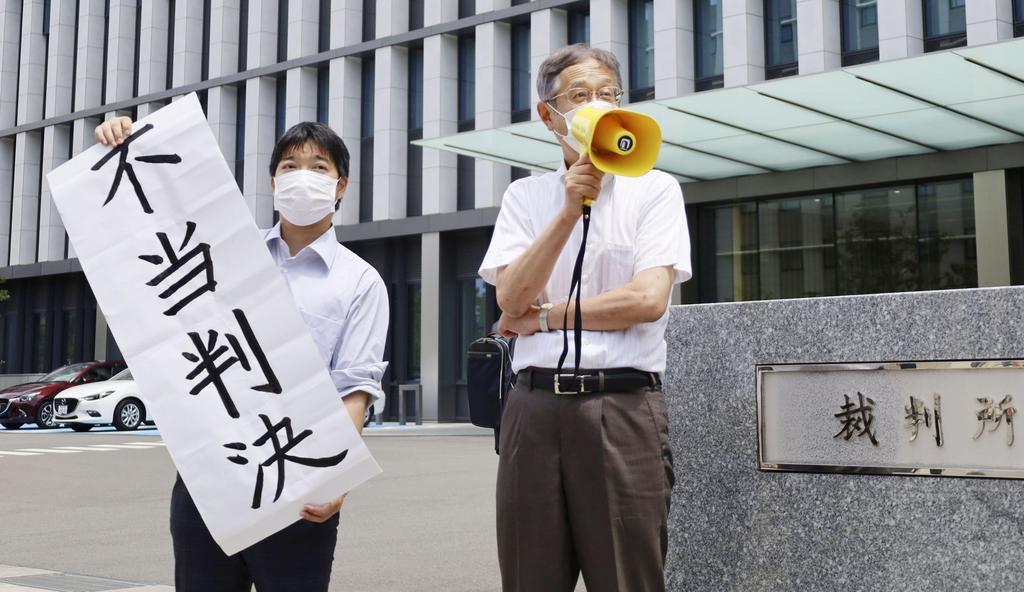 マイナンバー訴訟の判決を受け、不当判決と書かれた紙を掲げる住民側グループの男性=15日午後、福岡地裁